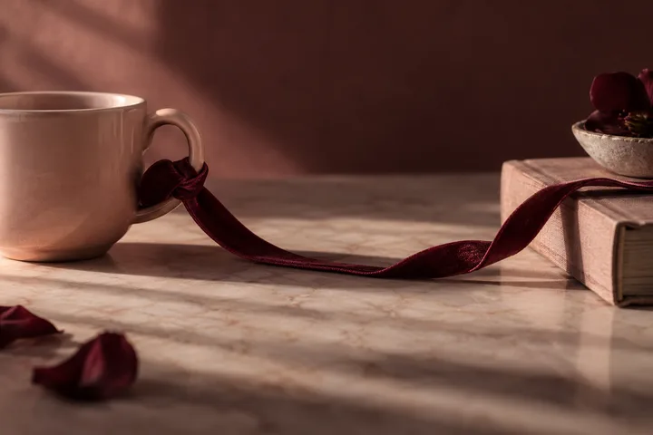 Blush cup and burgundy ribbon stretched between an open book and a small dish, evoking a relationship boundary and the choice to pause before re-engaging.